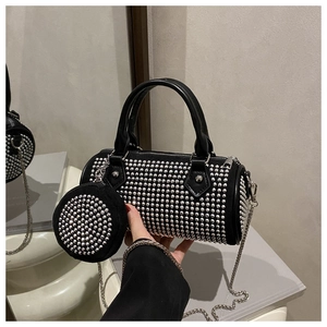 Detail of black cylindrical crossbody bag with silver studs and small round purse