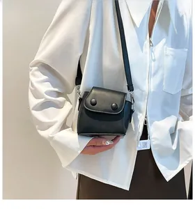 Detailed side view of a black mini leather crossbody bag with dual decorative buttons