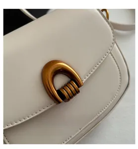 Détail du sac en cuir beige avec fermoir en U doré antique et coutures apparentes