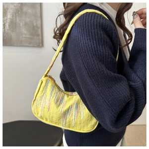 Detail of yellow baguette bag featuring embossed FF patterns and vibrant embroidery
