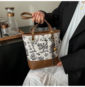 Detail of vintage canvas tote with leather trim, rabbit prints and gold bell charm