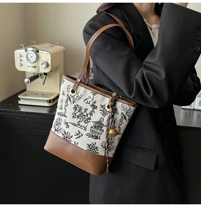 Detail of vintage tote bag featuring floral canvas, leather trim, and a gold bell charm