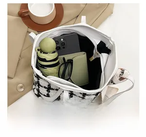 Vue intérieure d'un grand sac cabas en tweed noir et blanc montrant l'espace de rangement