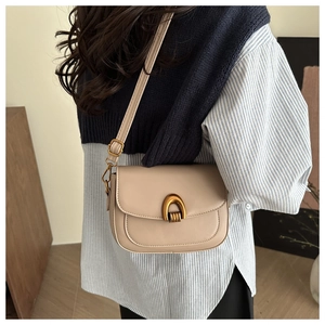 Détail du sac besace en cuir beige avec boucle dorée en arche et bandoulière réglable