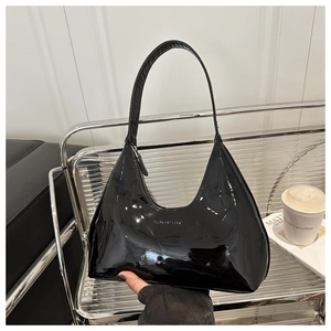 Close-up of black patent leather hobo bag on a silver mesh stand with a glossy finish
