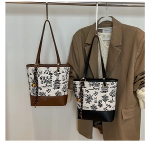 Detail of canvas tote bag featuring classic landscape print and leather trim details