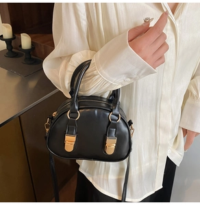 Dettaglio borsa a guscio nera con finiture dorate e fibbie in metallo eleganti