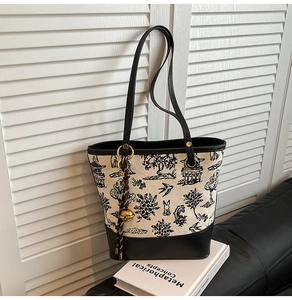 Détail du sac seau à broderie chinoise montrant la texture toile et les coutures cuir
