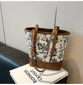 Detail of Chinese print canvas tote bag with brown leather trim and golden ball charm