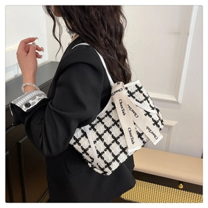 Détail du sac bandoulière en tweed à motif noir et blanc et bandoulière lettrée