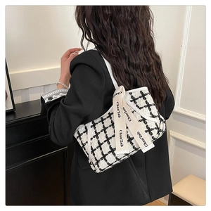 Détail du sac cabas à carreaux avec ruban décoratif porté par un mannequin en blazer