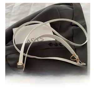 Detail of adjustable white leather strap with elegant gold metal buckle on a shoulder bag