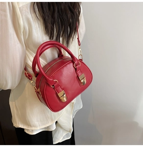 Model wearing a red mini Boston bag with gold hardware and a detachable strap