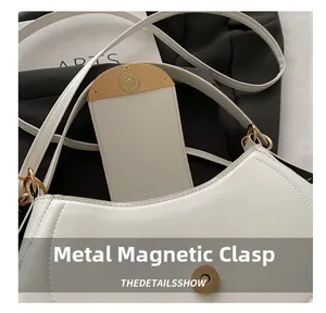 Close-up of the light gold magnetic buckle and lychee grain leather on a white handbag