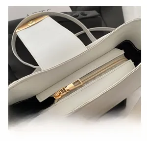Detail of white leather shoulder bag featuring a smooth gold zipper and black lining