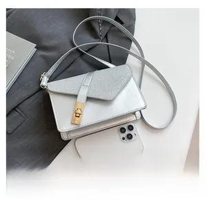 Silver metallic crossbody bag with gold buckle shown next to a smartphone for size reference