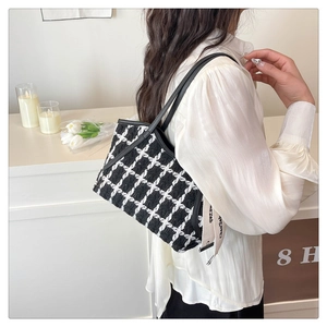 Détail du cabas en tweed noir et blanc avec bandoulière en cuir et ruban logo décoratif