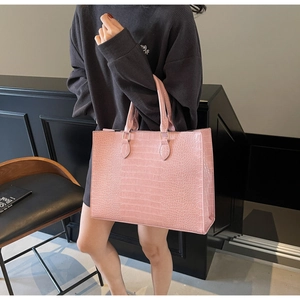 Detail of pink croc-effect tote bag showing refined texture and sturdy handles