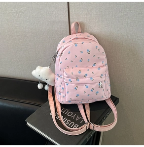 Details des rosa Nylon-Rucksacks mit blauem Blumenmuster und flauschigem Wolkenanhänger
