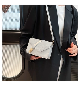 Detail of light gray crossbody bag with sequin flap and elegant gold turn-lock closure