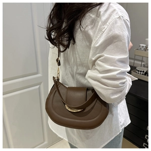 Détail du sac besace marron foncé avec boucle dorée en croissant et bandoulière cuir
