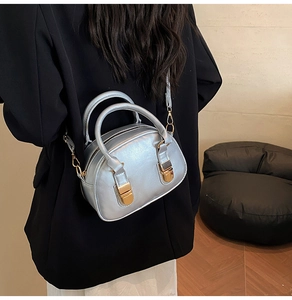 Borsa a conchiglia argento metallizzato indossata a tracolla da una modella per look