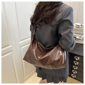 Dettaglio della borsa tote vintage marrone grande indossata con un blazer grigio