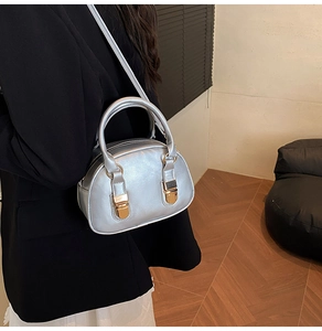 Model wearing a metallic silver bowling bag with gold buckles and dual handle detail