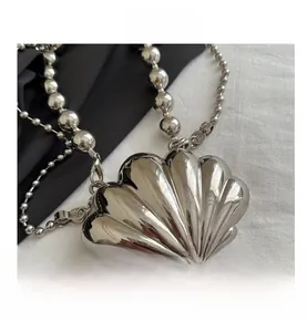 Close-up of metallic silver shell-shaped crossbody bag with beaded metal chain