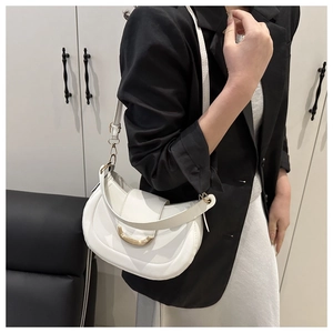 Detailed close-up of white semi-circle saddle bag with elegant gold metal ring clasp