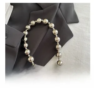 Detail of silver beaded metal shoulder strap with high-gloss finish and shell connector