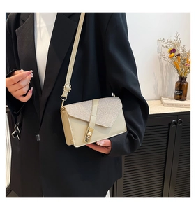 Detail of the chic beige crossbody bag featuring silver sequins and a gold square lock