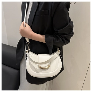 Detail of white saddle bag showing gold crescent buckle and dual strap on black blazer