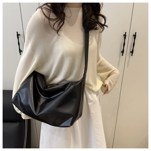 Modella che indossa una borsa a tracolla in pelle nera opaca dal design minimalista