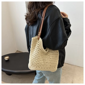 Detail of hand-woven beige crochet tote bag with durable brown leather shoulder strap