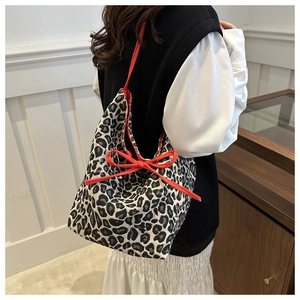 Détail du sac cabas léopard avec nœud rouge et finition en tissu texturé