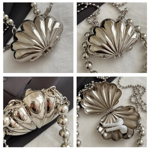 Macro detail of silver shell-shaped mini bag with metallic texture and beaded chain