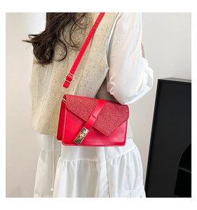 Detail of red leather crossbody bag with glitter finish and gold metal clasp on model