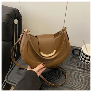 Close-up of caramel brown crescent crossbody bag with quilted leather and gold buckle