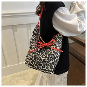 Detail of leopard print canvas tote bag featuring a vibrant orange decorative bow