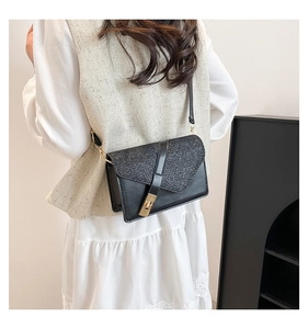Detail of crossbody bag featuring black glitter flap and golden rotating metal lock