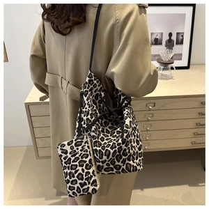 Leopard print drawstring tote bag with matching coin purse shown on a shoulder strap