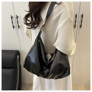 Dettaglio della grande borsa tote in pelle nera con fibbia dorata sulla tracolla indossata