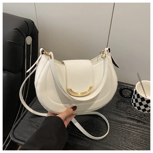 Close-up of white crescent shoulder bag featuring premium gold hardware and leather texture