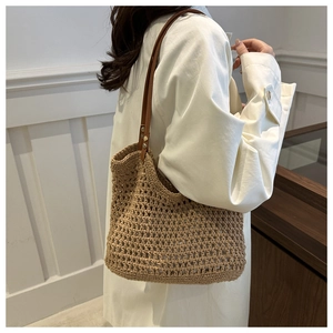 Detail of woven straw bucket bag with leather strap and metal rivets for summer