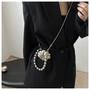 Silver shell-shaped mini crossbody bag with bead handle and metal chain on black suit