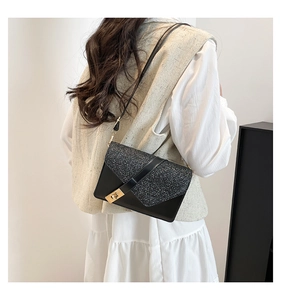 Side view of black crossbody bag with sequined flap and golden square lock