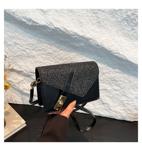 Detail of black sequined flap and golden square lock on a vintage small crossbody bag