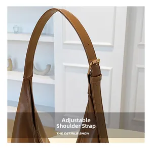 Detail of adjustable leather shoulder strap with golden metal buckle on brown tote bag