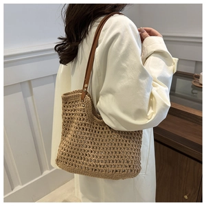 Detail of hollow woven cotton shoulder bag with brown leather straps and metal rivets